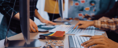A dynamic workspace captures creative professionals collaborating on design projects, showcasing color swatches and modern technology in a vibrant atmosphere.の写真素材