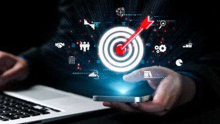 A business professional engages with a smartphone, visualizing goals through digital icons representing strategy, success, and technology in a dynamic business environment.の写真素材