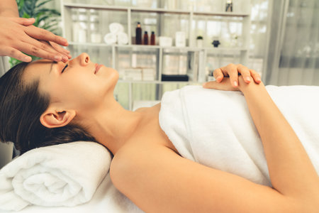 Caucasian woman enjoying relaxing anti-stress head massage and pampering facial beauty skin recreation leisure in dayspa modern light ambient at luxury resort or hotel spa salon. Quiescentの写真素材