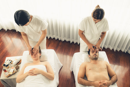 Caucasian couple enjoying relaxing anti-stress head massage and pampering facial beauty skin recreation leisure in dayspa modern light ambient at luxury resort or hotel spa salon. Quiescentの写真素材