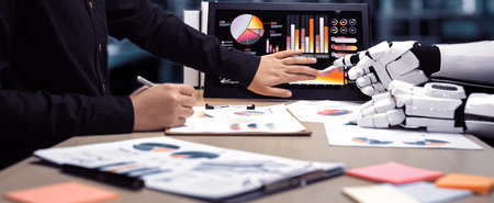A human hand collaborates with a robotic hand in a contemporary office, analyzing colorful graphs...