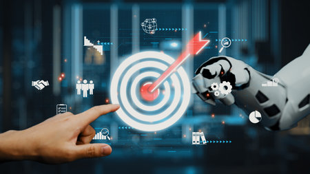 A close-up view of a human hand and a robotic hand reaching toward a glowing target, symbolizing collaboration in digital business environments for achieving goals.の写真素材