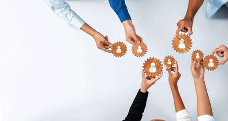 This image showcases diverse hands connecting gears, symbolizing networking and cooperation in a modern business setting, highlighting teamwork and collaboration.の写真素材