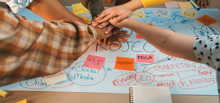 Enthusiastic teamwork is depicted as diverse hands unite over a detailed brainstorming sheet filled with colorful notes, illustrating a dynamic marketing project planning session.の写真素材