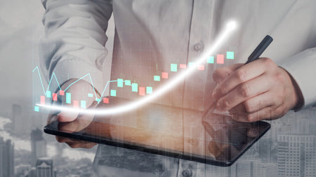A business professional engages with data trends on a tablet, surrounded by financial graphs and...