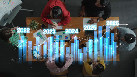 A diverse business team reviewing financial data, charts, and projections on growth from 2022 to...