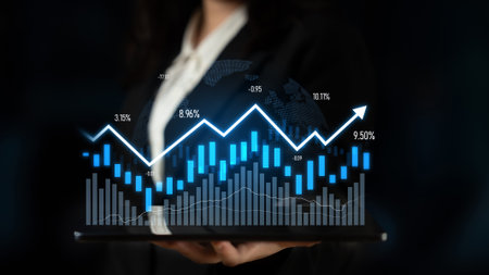 A business professional holds a tablet displaying digital graphs and charts, illustrating financial data trends and market growth in a modern office setting.の写真素材