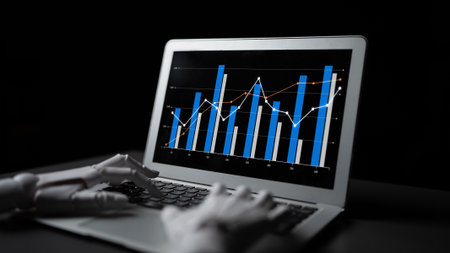 A robotic hand interacts with a laptop showcasing colorful financial graphs against a dark background, symbolizing the intersection of technology and finance.の写真素材