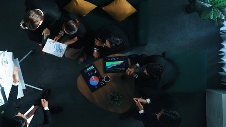 Top down view of business people listen businessman present idea while making decision. Group of diverse team making a decision to invest start up project while hold tablet display graph. Directorate.の写真素材