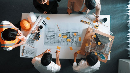 Top down view of skilled engineer team talking about house construction. Aerial view of group of architect or designer discussing and writing sticky note to brainstorm about blueprint.の写真素材