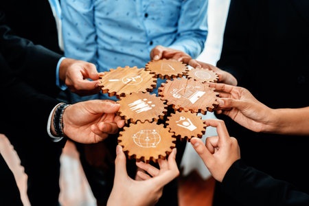 A dynamic group of professionals engaging in teamwork with wooden gears representing various business strategies, showcasing collaboration and innovative thinking.の写真素材