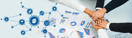 A diverse team collaborates in a modern workspace, focusing on data analysis and strategic planning. Hands unite over charts, illustrating teamwork and innovation for success.の写真素材