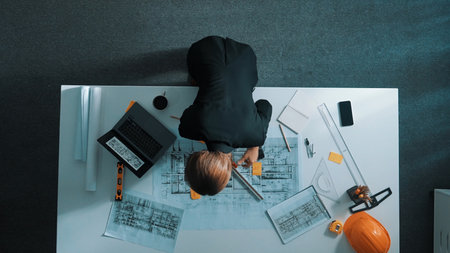 Top view of manager using ruler to measure project plan while looking at building construction on laptop screen. Aerial view architect engineer analyzing and planning about structure.の写真素材