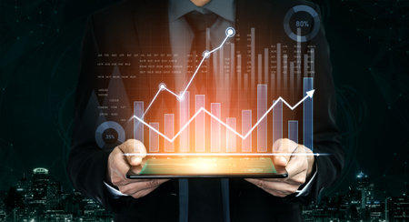 A business professional holds a tablet displaying financial graphs, symbolizing data analysis and...