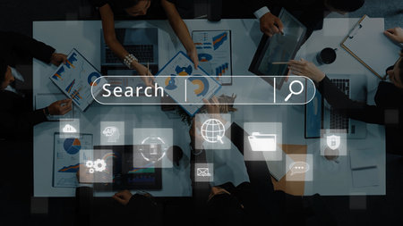 A diverse business team collaborates over data analysis documents, utilizing laptops and a digital...