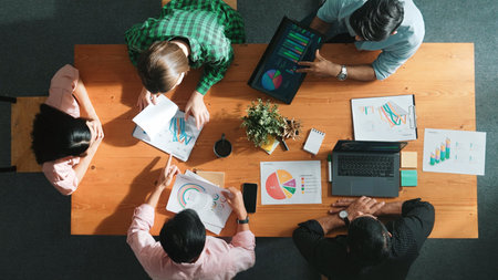 Top view of project manager using tablet to analyze data and financial chart while marketing team working together to brainstorm marketing campaign or planning strategy at meeting room. Convocation.の写真素材