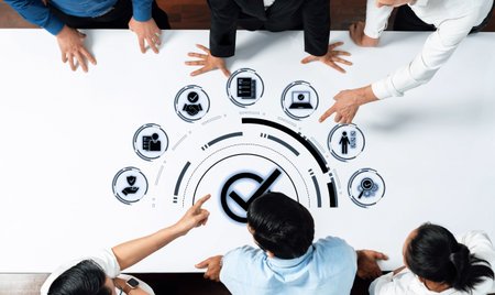 Team Collaboration Around Digital Interface with Icons Representing Business Concepts and Data Analytics in Modern Workspace Trope.の写真素材