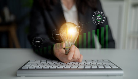 A business professional presents an illuminated light bulb to symbolize innovative ideas and future growth strategies, focusing on sustainability and net zero emissions by 2040. Gantryの写真素材