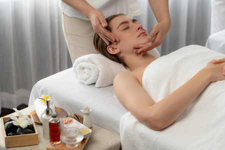 Caucasian woman enjoying relaxing anti-stress head massage and pampering facial beauty skin recreation leisure in dayspa modern light ambient at luxury resort or hotel spa salon. Quiescentの写真素材