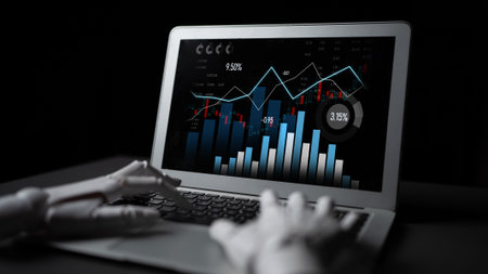 A futuristic scene showing a robot hand interacting with a laptop displaying financial graphs and analytics data, symbolizing technology in business and innovation.の写真素材