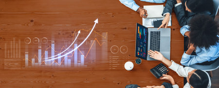 A diverse business team collaborates during a meeting, analyzing financial data with graphs and...