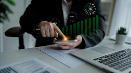 A business professional examines growth data on a smartphone, highlighting trends in sustainability and environmental impact in a modern office environment.の写真素材