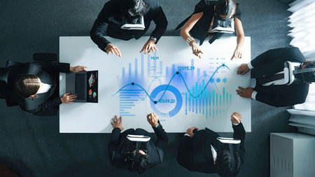 A business team engages in a collaborative meeting using virtual reality headsets, analyzing data on a digital screen in a modern office environment.の写真素材