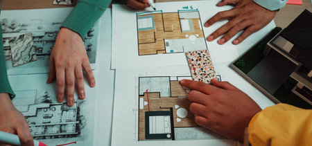 Two individuals engage in a dynamic collaboration on architectural planning, surrounded by sketches and layouts, showcasing the creative process in design.の写真素材