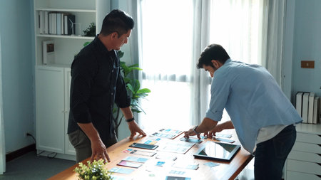 Top down view of business people talking about UX UI design while project manager present marketing idea at meeting table with paper and tablet. Diverse team brainstorming idea.の写真素材