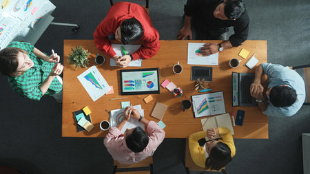 Top view of businesswoman sharing idea while standing at whiteboard while manager asking question at table with tablet displaying financial graph. Female leader pointing at board.の写真素材