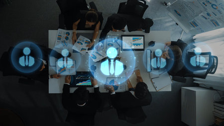 Aerial view of a team collaborating in an office environment, utilizing digital interfaces and engaging in data analysis, strategic planning, and discussions. Rasterの写真素材