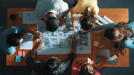 Top down view of civil engineer team writing at blueprint at meeting table with color palettes. Group of diverse people planning and taking a note while manager looking at project plans. Symposium.の写真素材