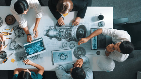 Top down aerial view of smart engineer team working together to design turbine engine. Professional technician discussing about jet engine construction while pointing at part of engine.の写真素材