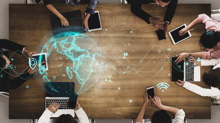 A diverse business team collaborates in a modern office setting, utilizing various digital devices for communication and strategy, highlighting global connectivity and innovation.の写真素材