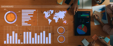 A top view of a business dashboard with various charts, graphs, and a world map on a wooden table....