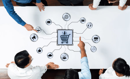 Business professionals engage in a collaborative strategy session, focusing on digital marketing and e-commerce concepts, surrounded by visual elements on a table.の写真素材
