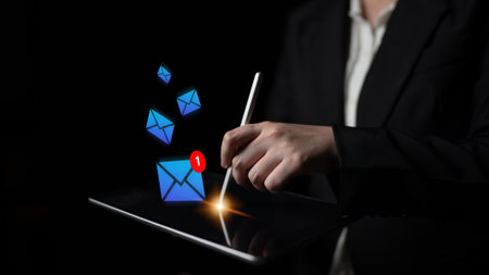 Businessperson interacts with digital tablet to check email notifications. Floating letters...