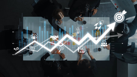 Aerial view of a business meeting featuring data visualization and growth projections, showcasing teamwork, innovative strategies, and collaborative planning in a modern office setting. Rasterの写真素材