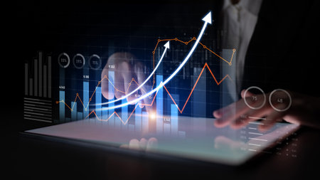 A businessman engages with a tablet displaying financial graphs and charts, illustrating trends and...