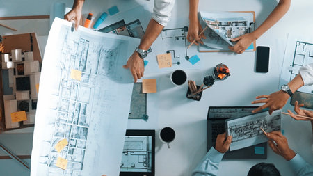 Group of diverse team planning strategy while sitting at table with project plan. Top aerial view of...