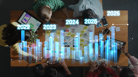A vibrant overhead view of a business strategy meeting showcasing professionals analyzing growth charts and discussing future plans using various devices. Rasterの写真素材