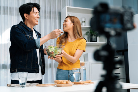Cooking show live streaming with two chef influencers making mixed salad, all ingredients with dressing with good taste for easy special menu served with bun bread on table record by camera. Infobahn.の写真素材