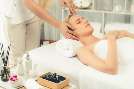 Caucasian woman enjoying relaxing anti-stress head massage and pampering facial beauty skin recreation leisure in dayspa modern light ambient at luxury resort or hotel spa salon. Quiescentの写真素材