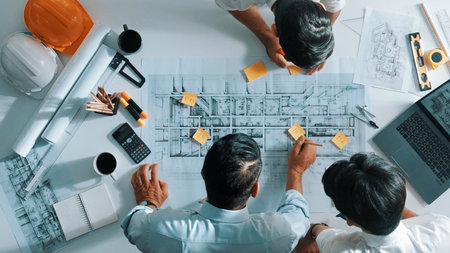 Top down aerial view of interior designer writing at sticky note while planning design with engineer team. Group of diverse architect and skilled manager looking at building construction.の写真素材