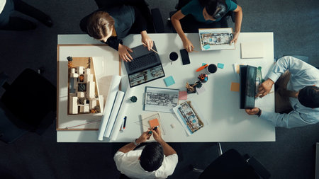 Architect team discussing and pointing and presenting blueprint to interior designer. Aerial view professional business people brainstorming building interior at table with house model.の写真素材