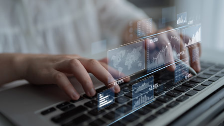 A person interacts with a laptop displaying digital financial data and graphs, illustrating data analysis and technology impact on finance and business decisions.の写真素材