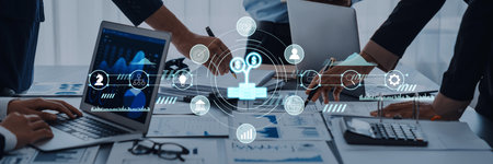 A dynamic team in a modern office uses laptops and data analysis tools to explore business strategies, enhancing collaboration and productivity through innovative technology.の写真素材