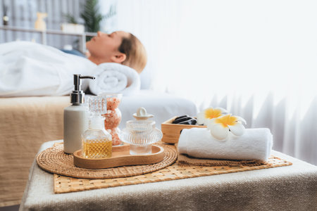 Aromatherapy massage on daylight ambiance or spa salon composition setup with focus decor and spa accessories on blur woman enjoying blissful aroma spa massage in resort or hotel background. Quiescentの写真素材