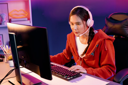 Host channel of Asian girl streamer concentrating online game wearing headphones pastel color...