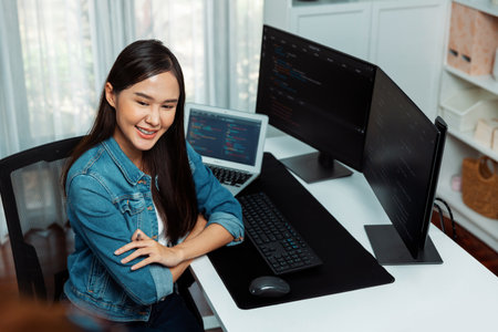 Young Asian IT developer looking out to present with online information on pc with coding program...
